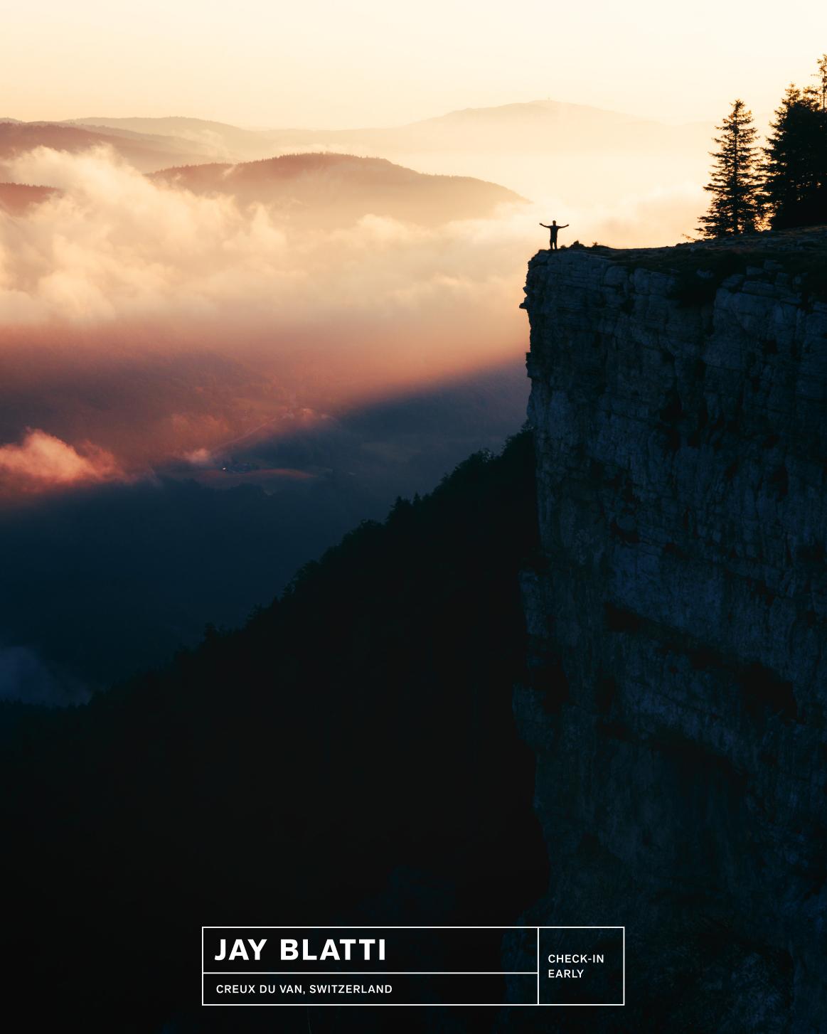 Adventurer in Mammut gear stands with arms raised atop a cliff at sunset, overlooking misty mountains and dramatic clouds.