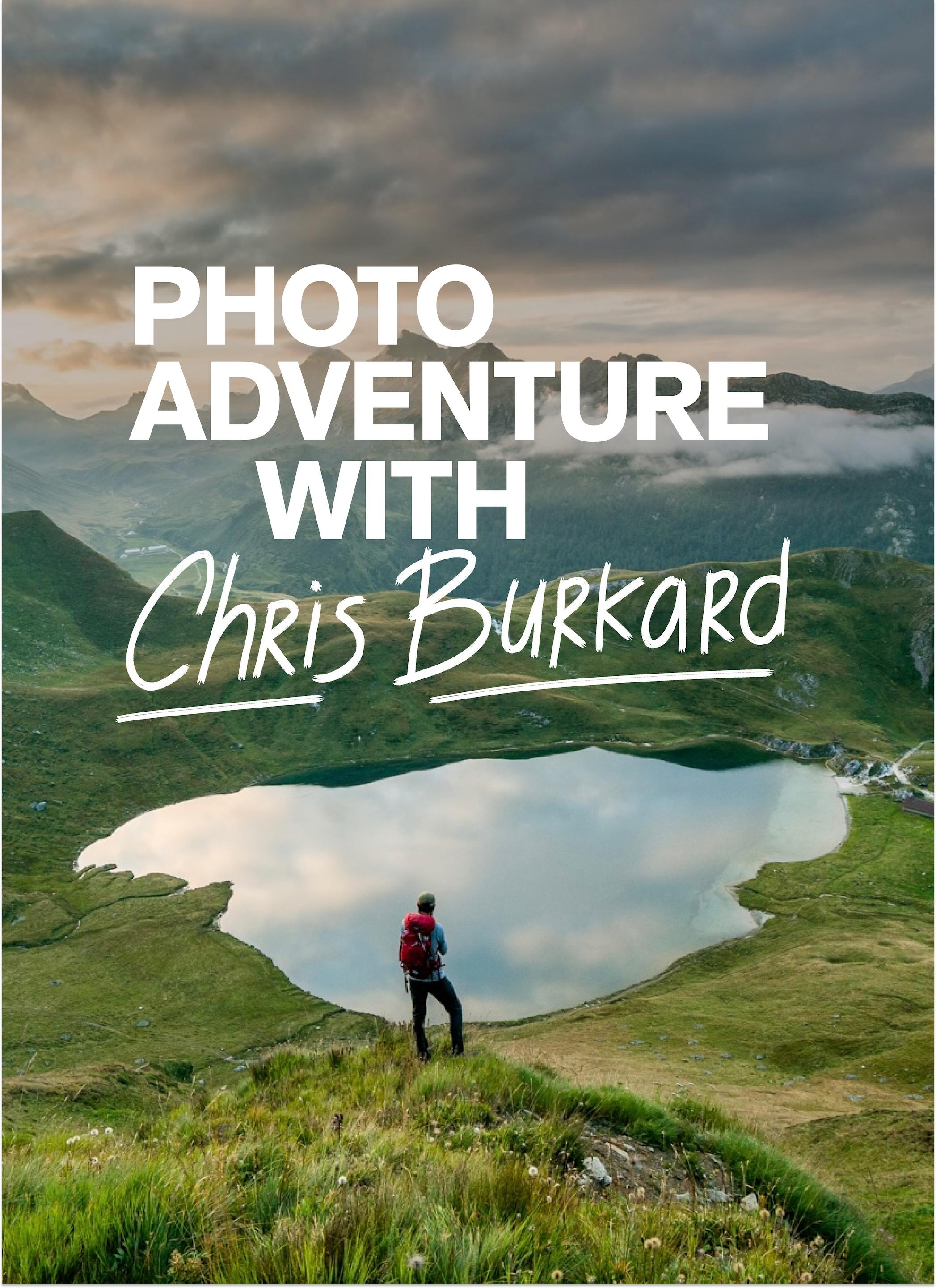 Person wearing Mammut backpack stands on grassy hill overlooking lake, with text "Photo Adventure with Chris Burkard".