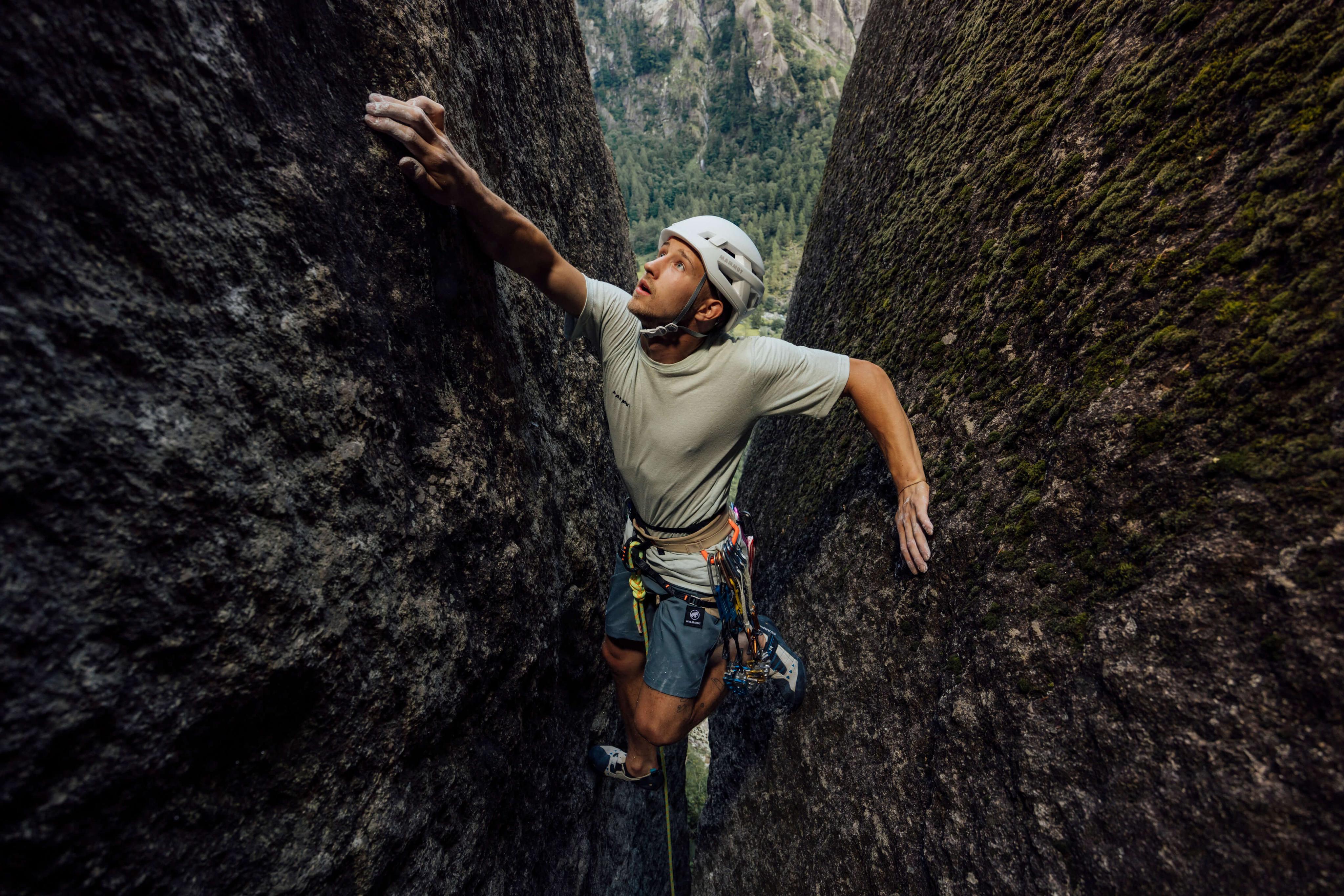 A man scaling a rock wall wearing Mammut climbing gear, demonstrating rock climbing with professional mountaineering equipment.