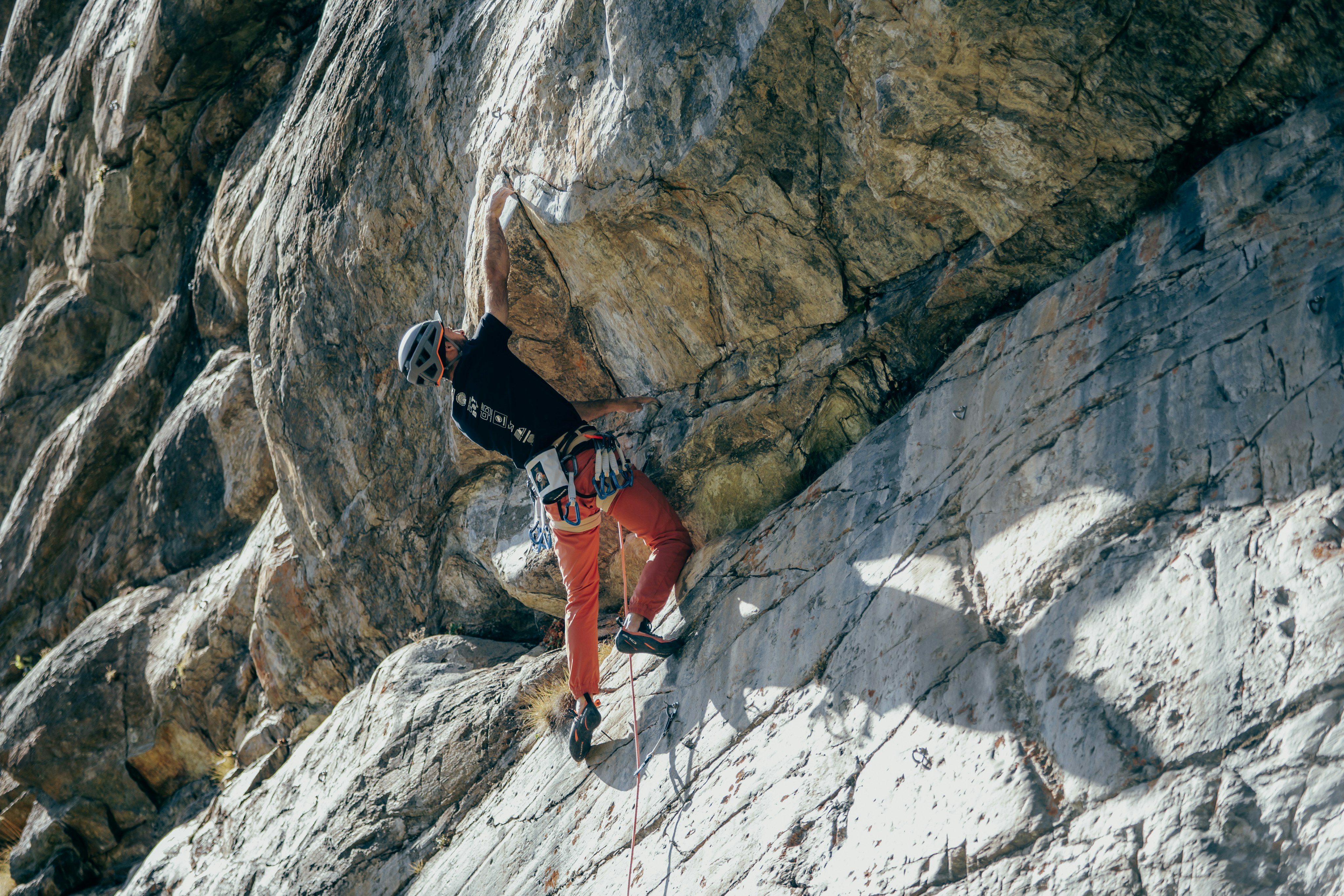 Person wearing Mammut protective gear rock climbing on a steep rock face.