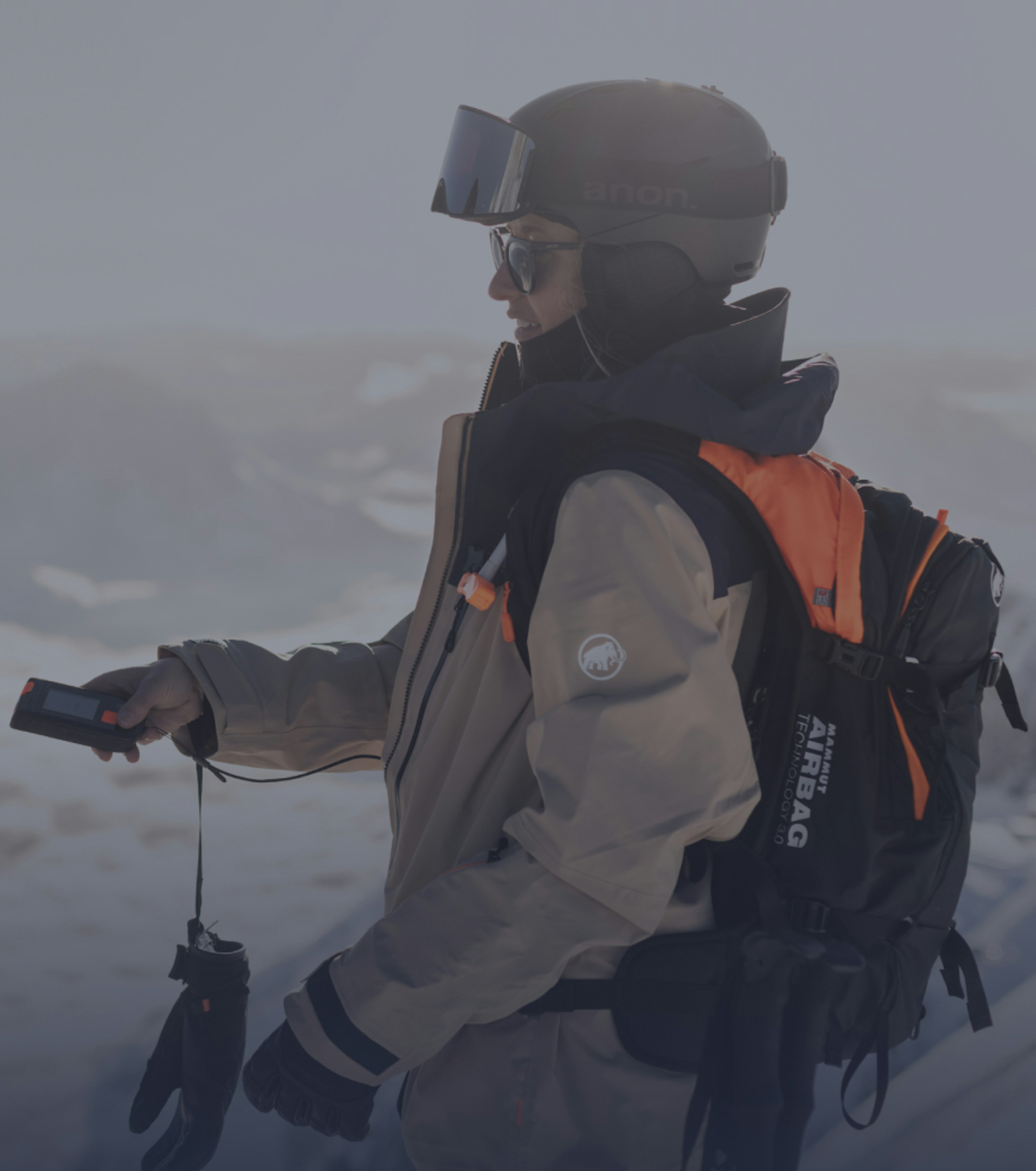 Skier in Mammut gear with backpack and helmet navigating a snowy mountain terrain using an avalanche safety device.