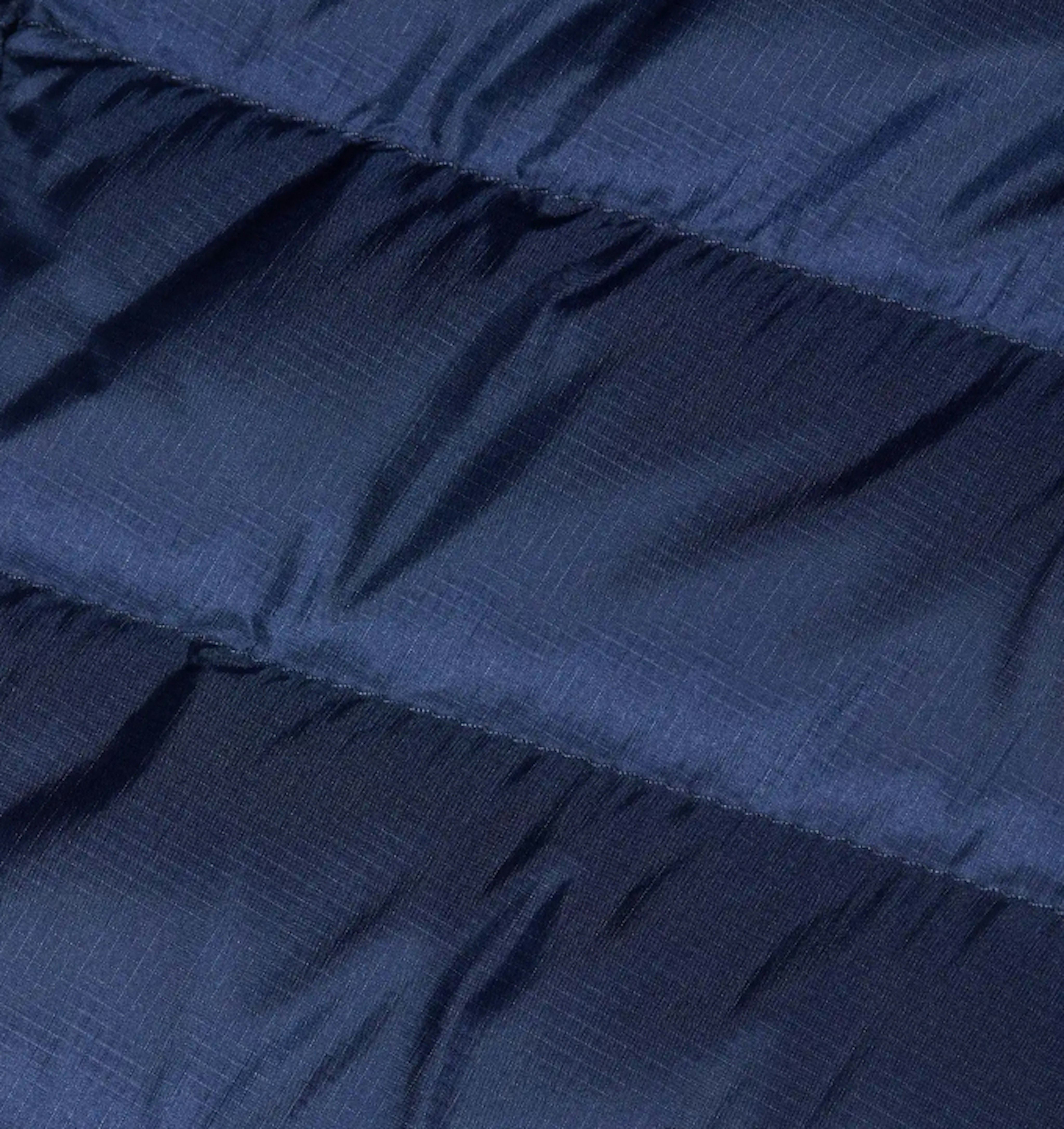 Close-up of a Mammut dark blue quilted fabric called dry down with horizontal stitching lines, highlighting its textured and padded surface perfect for mountaineering gear.