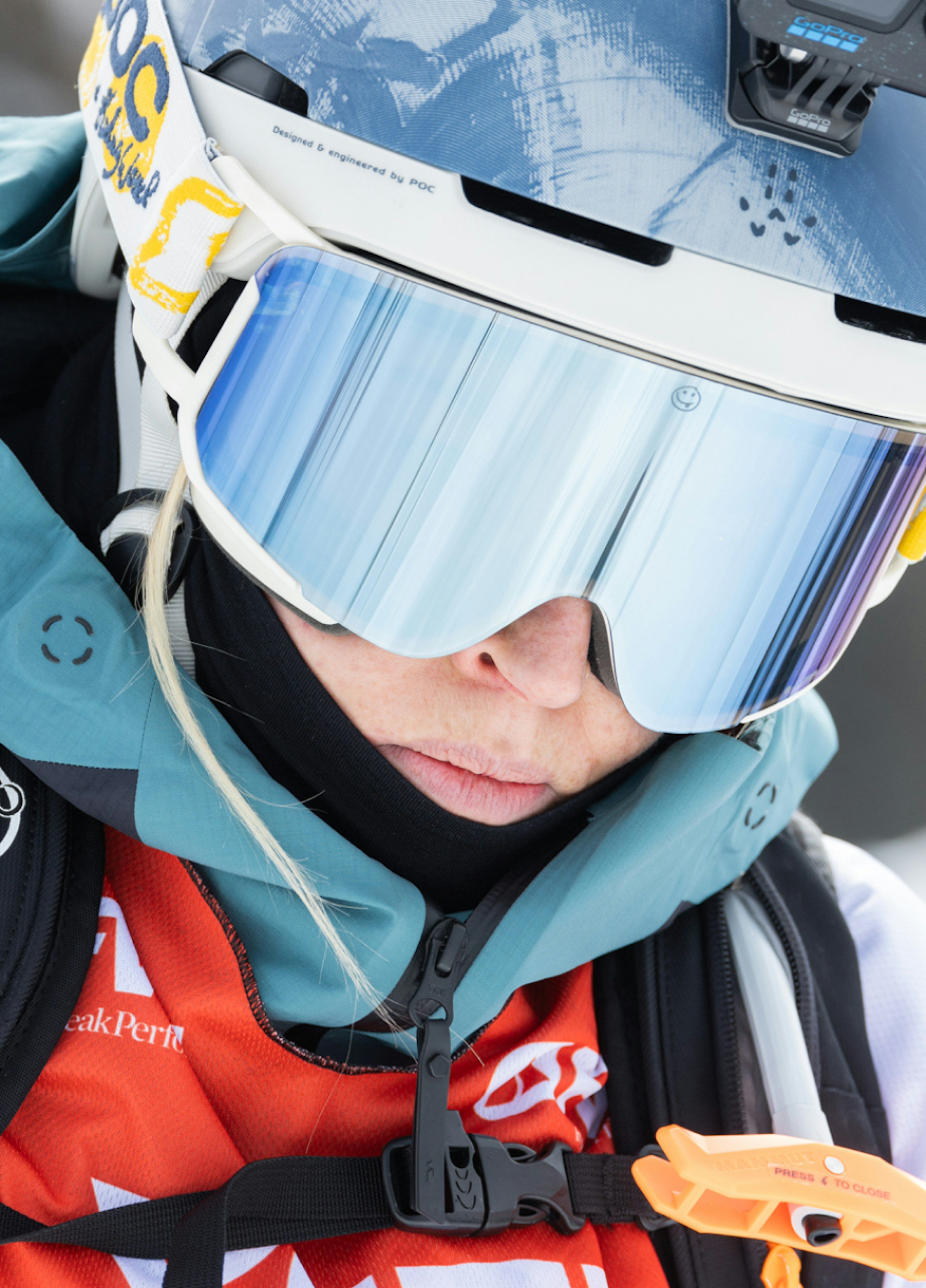 A skier wearing Mammut ski gear, including Mammut reflective goggles and a helmet, looks down with intense focus.